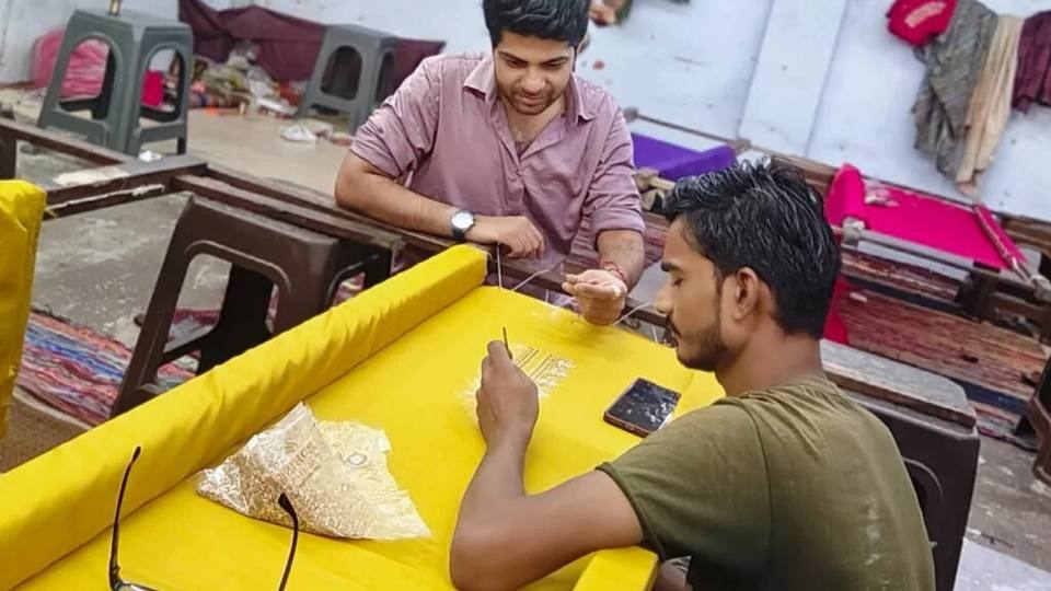Karigars working a fabric panel on a khatli frame in the Kanya Creation workroom