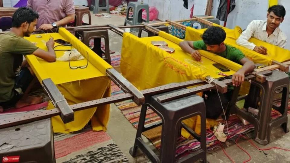 A row of khatli frames in use across the Kanya Creation workroom floor